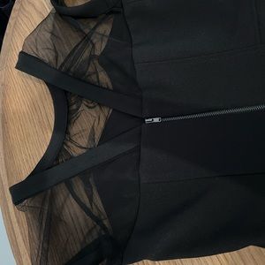 An elegant cocktail dress in black with sheer neckline and cap sleeves.